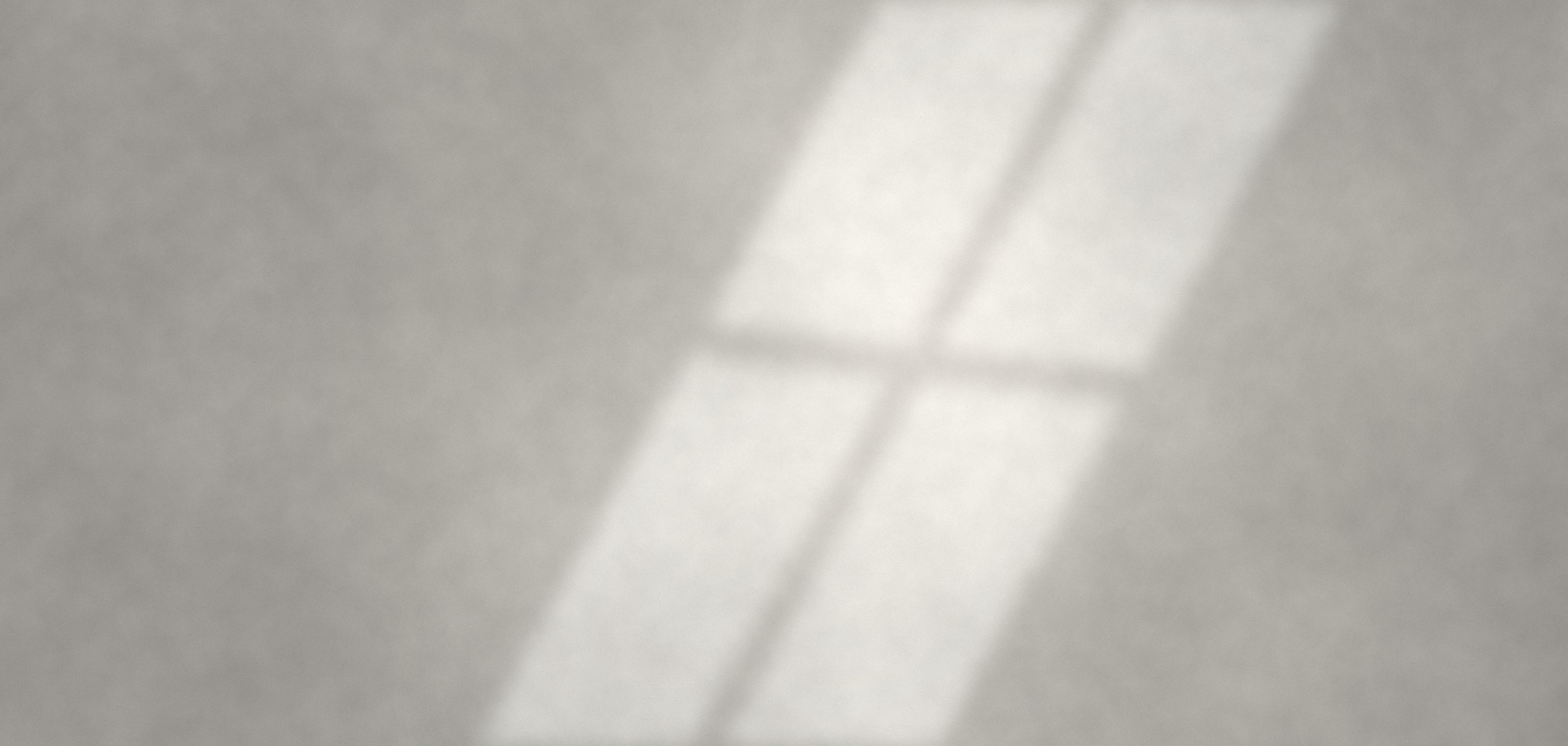 Soft window light falling across a pale stone wall